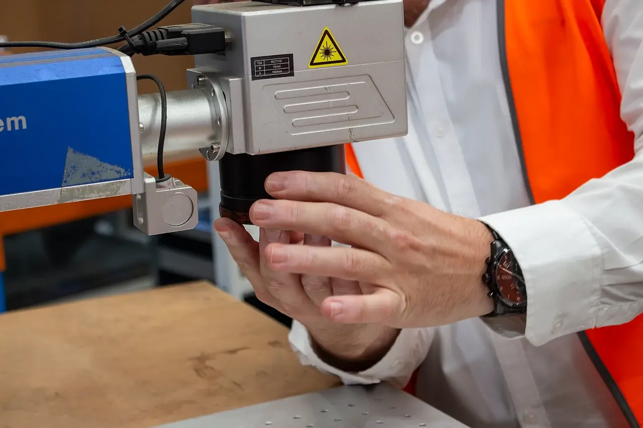 A technician adjusting the head of a laser-marking rig in the workshop