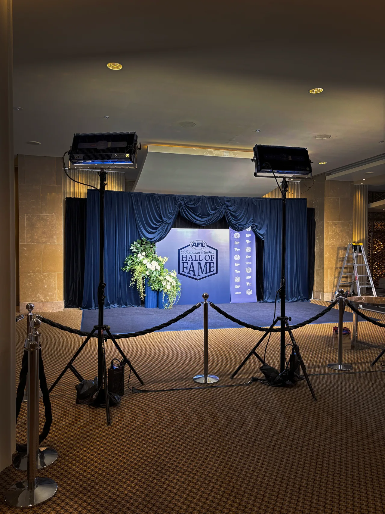 Blue swagged drapes framing a media wall backdrop with floral arrangements at Crown