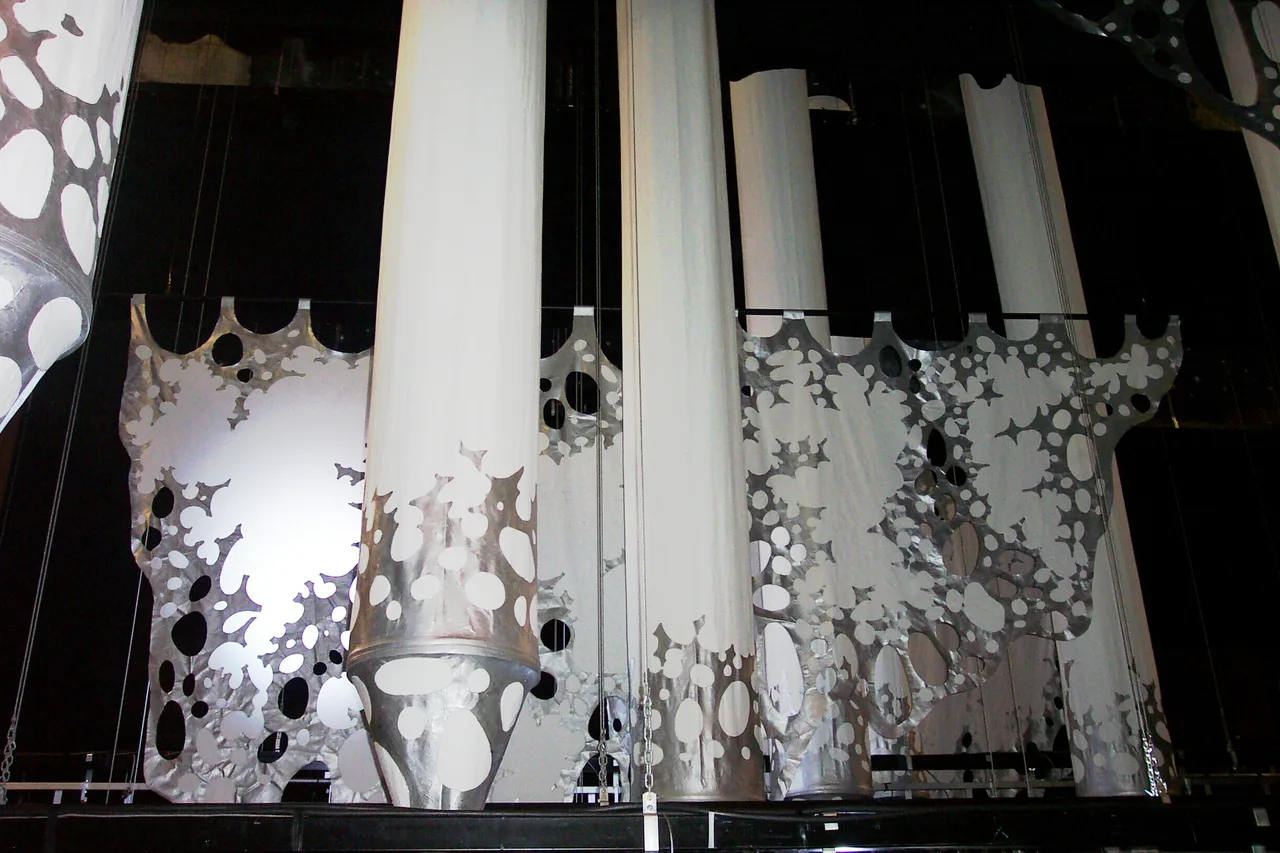 White fabric columns and silver cutout drape panels flown as scenic elements