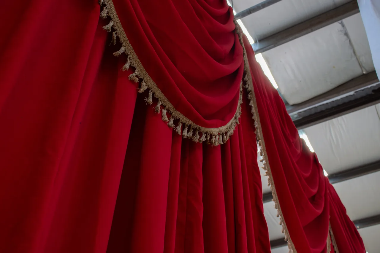 Red velvet swagged drapes with gold tasselled fringe in the workshop