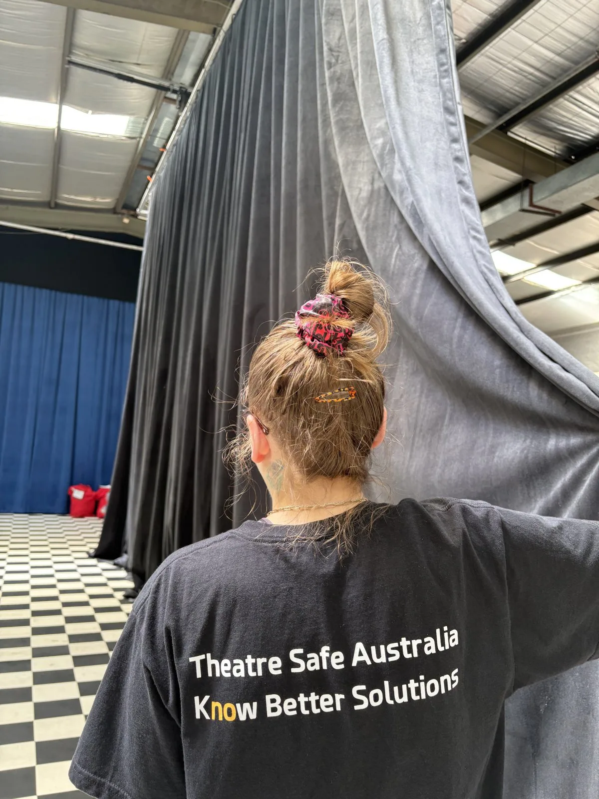 A staff member working among hung grey and black drapes during cleaning