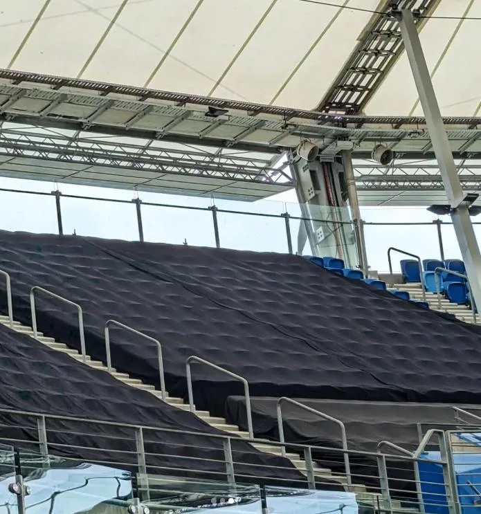 Black seat-kill covers draped over tiered stadium seating banks