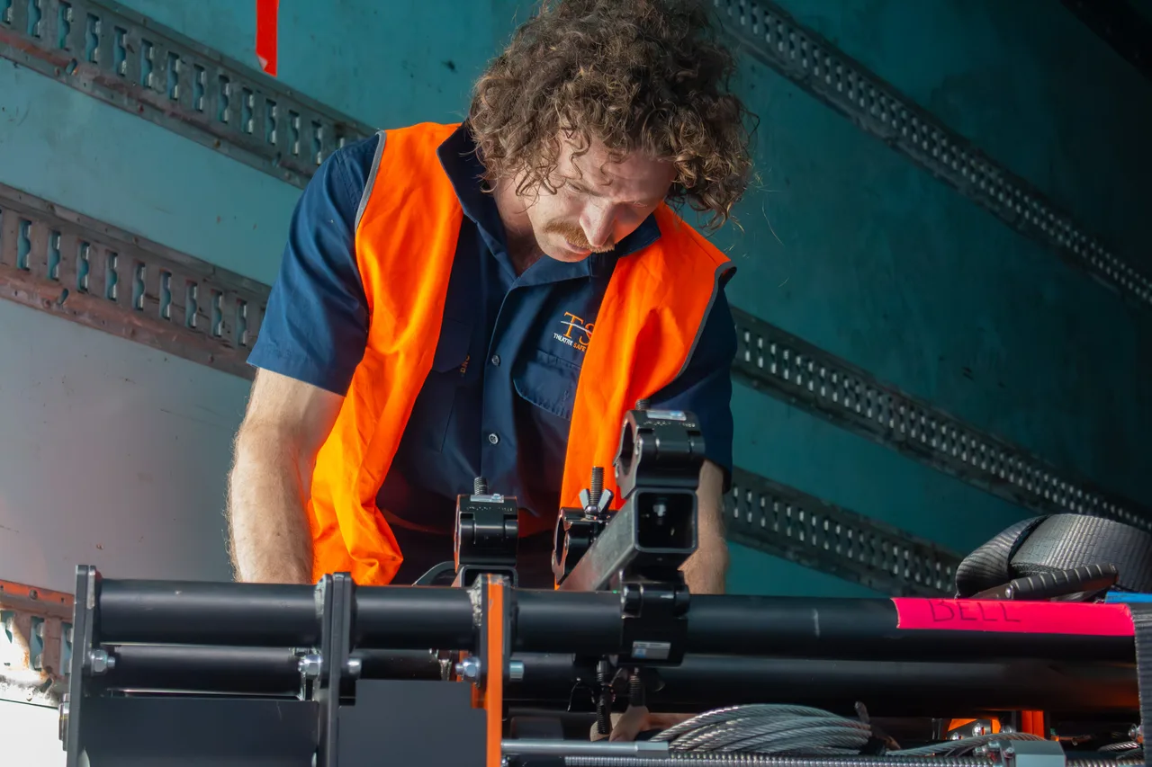 A crew member securing a Hercules winch and coiled wire rope inside a truck during load-out