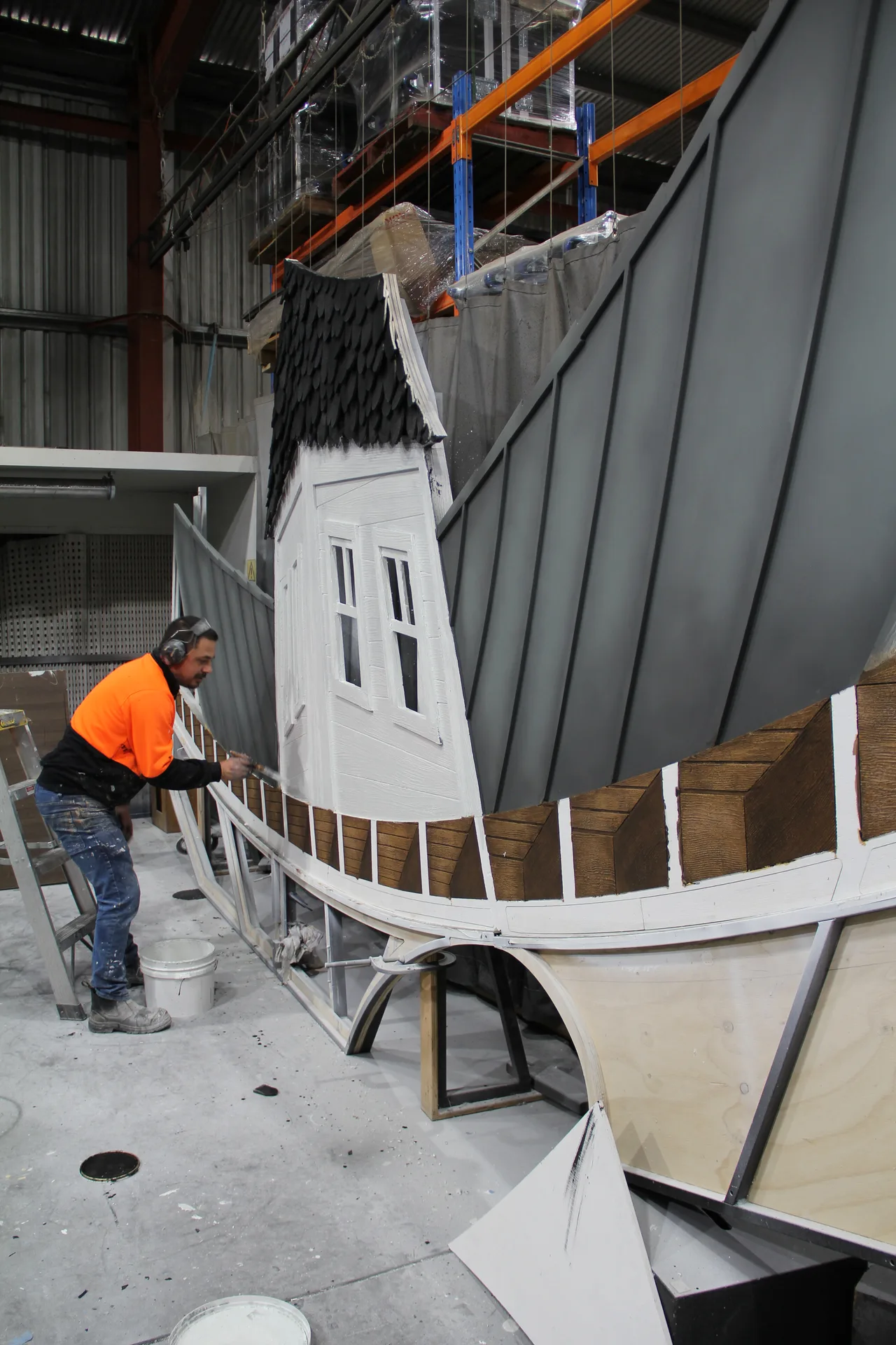 Scenic artist painting the weatherboard cladding of the haunted-house facade