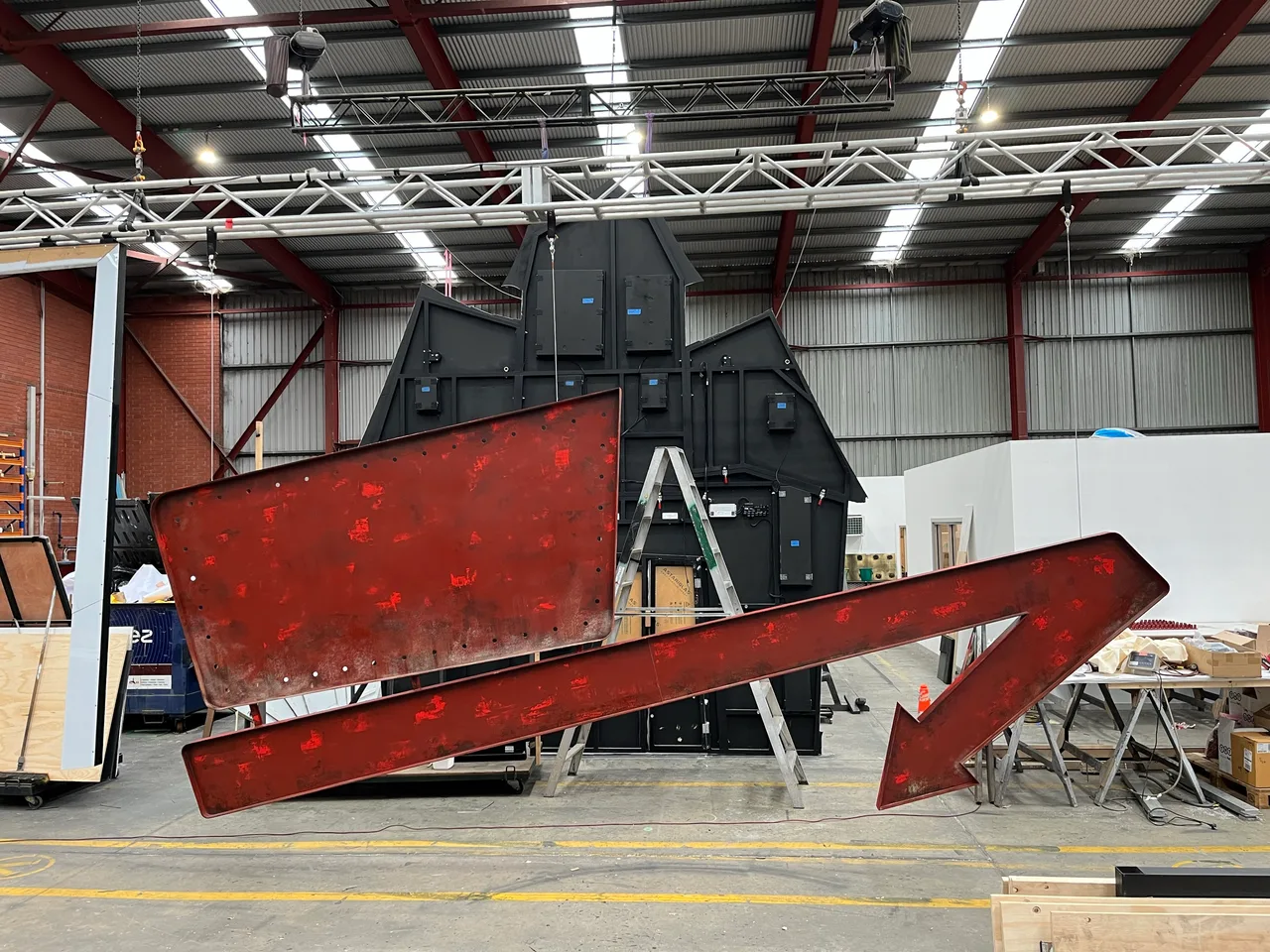 Distressed red arrow sign in front of the house set piece in the workshop