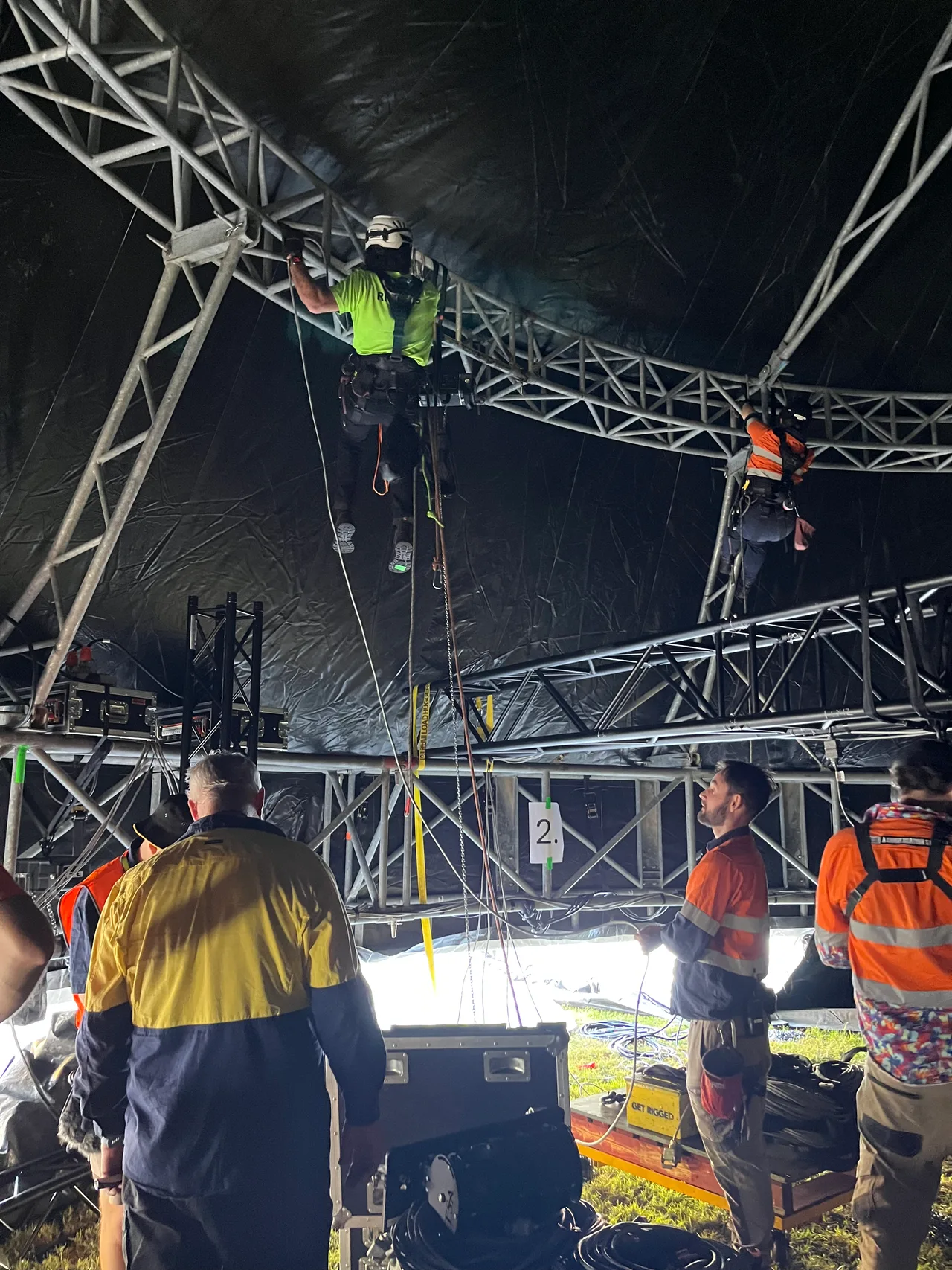 Riggers on rope access beneath the curved truss canopy