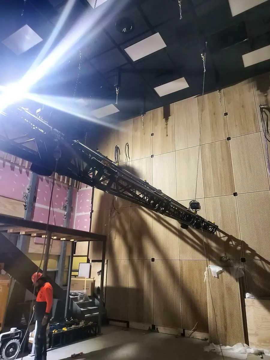 A truss flown into position on site under a work light during the media-centre fit-out.