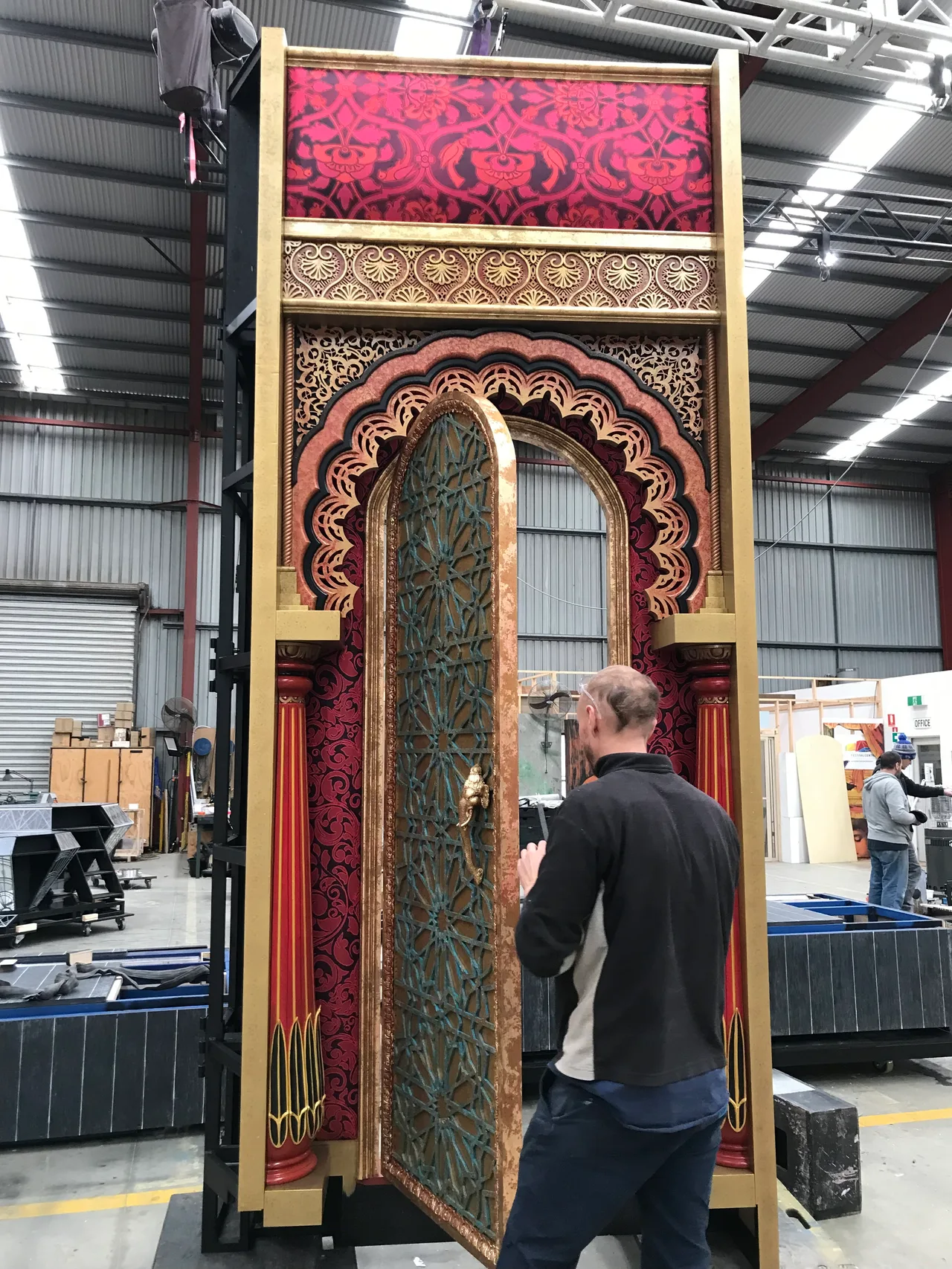 Craftsman fitting a latticework door into an ornate archway unit