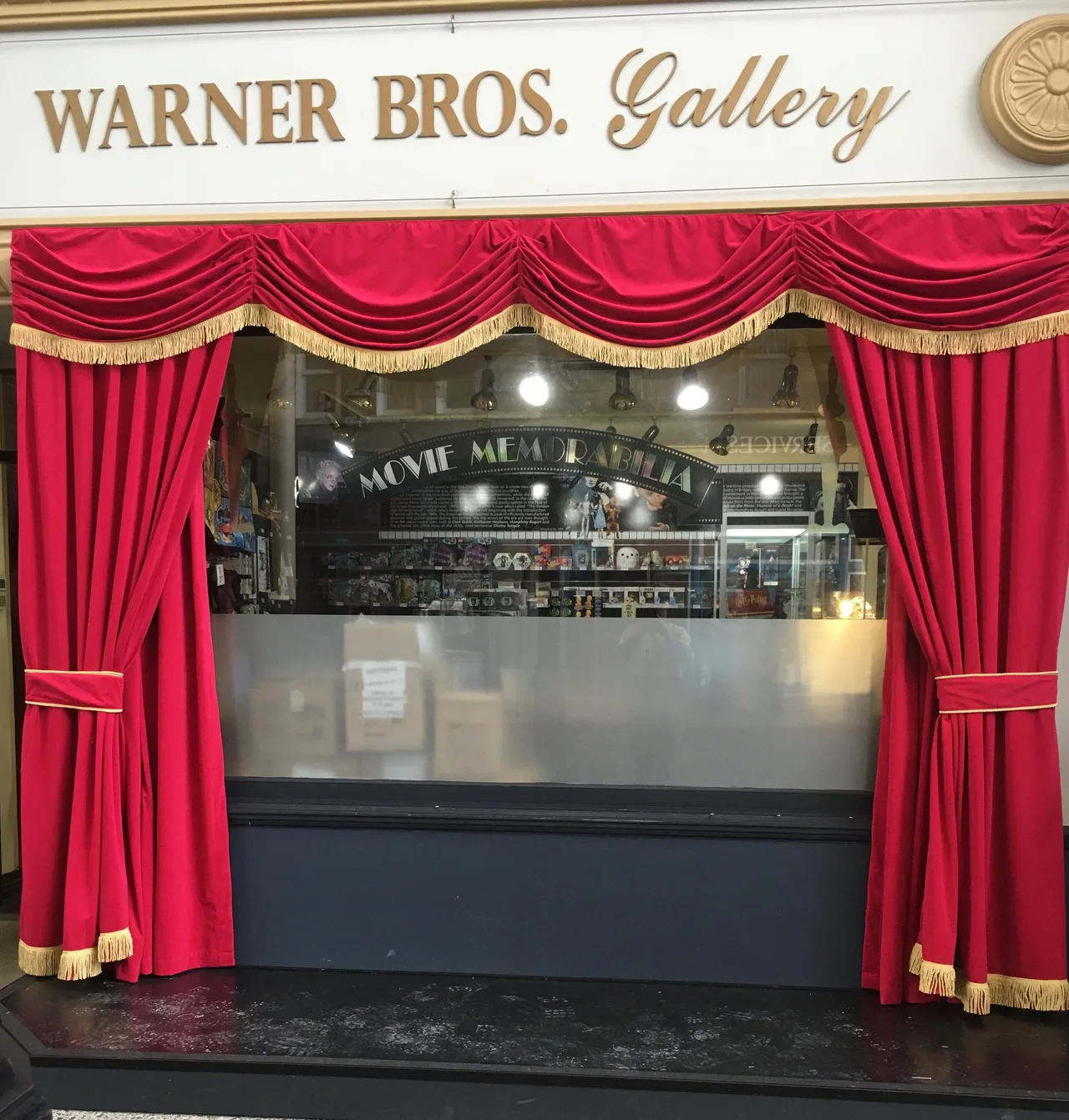 Red velvet swags with gold fringe framing the Warner Bros. Gallery shopfront at Movie World