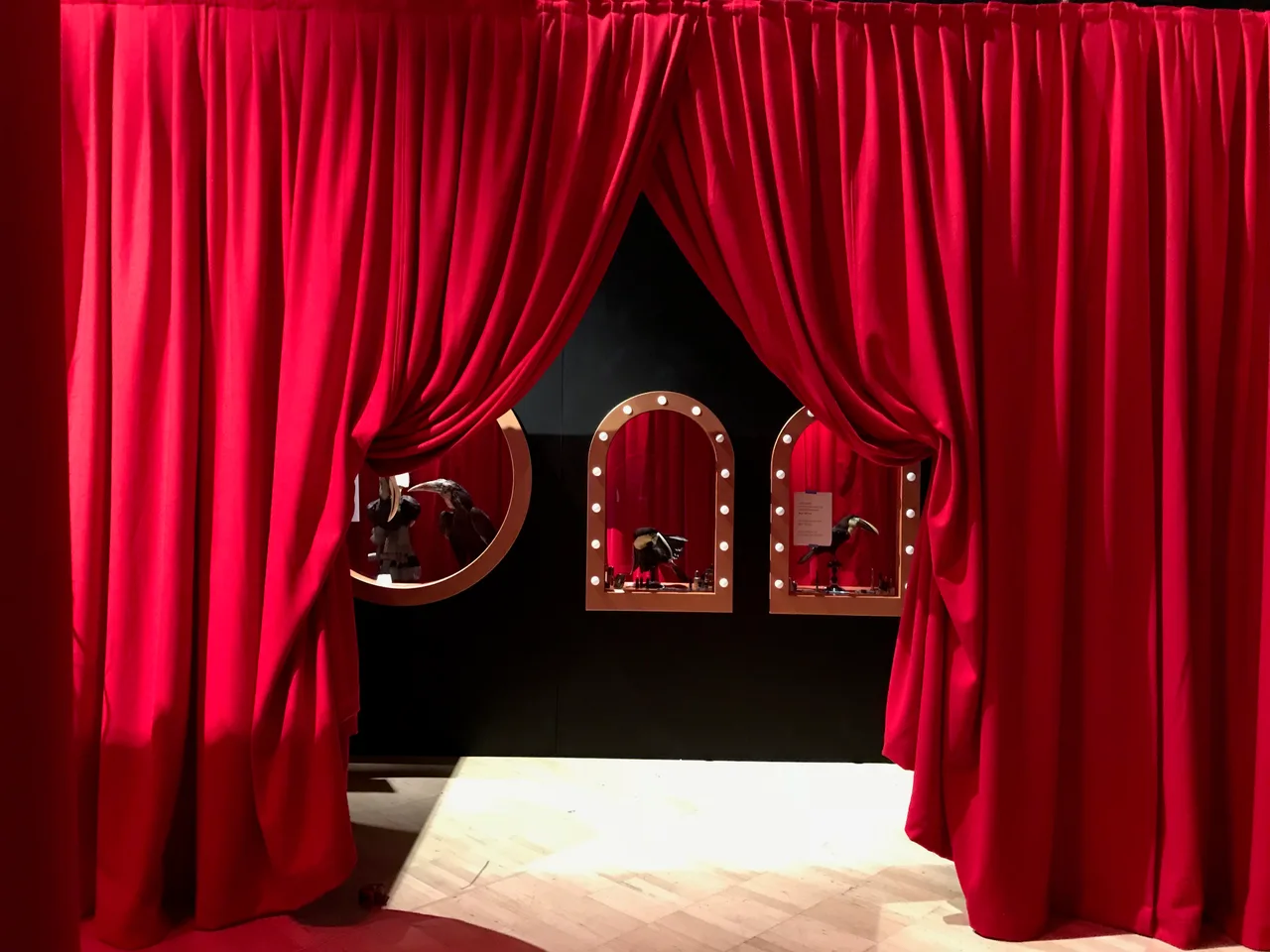Swagged red drapes framing a doorway to arched mirror displays at Melbourne Museum