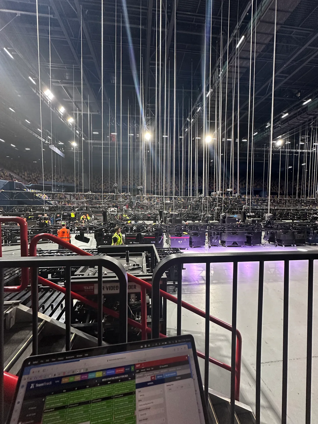 Arena floor with dozens of rigging drop lines, hoisted truss and production equipment mid-load-in