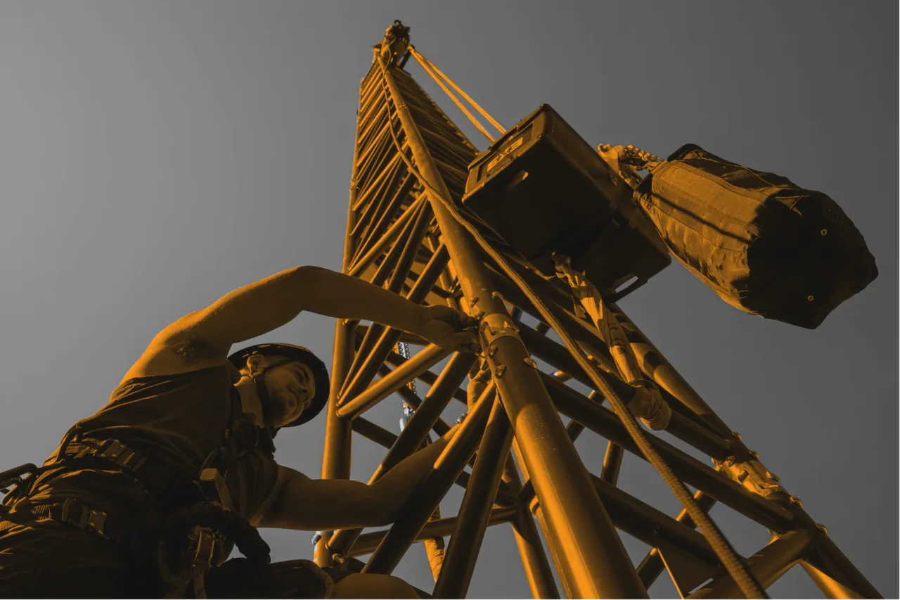 Rigger working at height beside a truss tower with chain hoists overhead