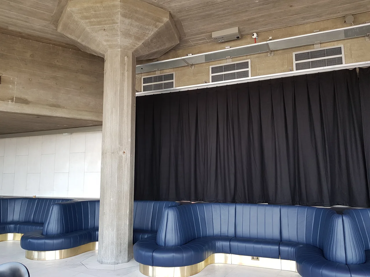 Black drapes on a ceiling track closing off a lounge with curved banquette seating